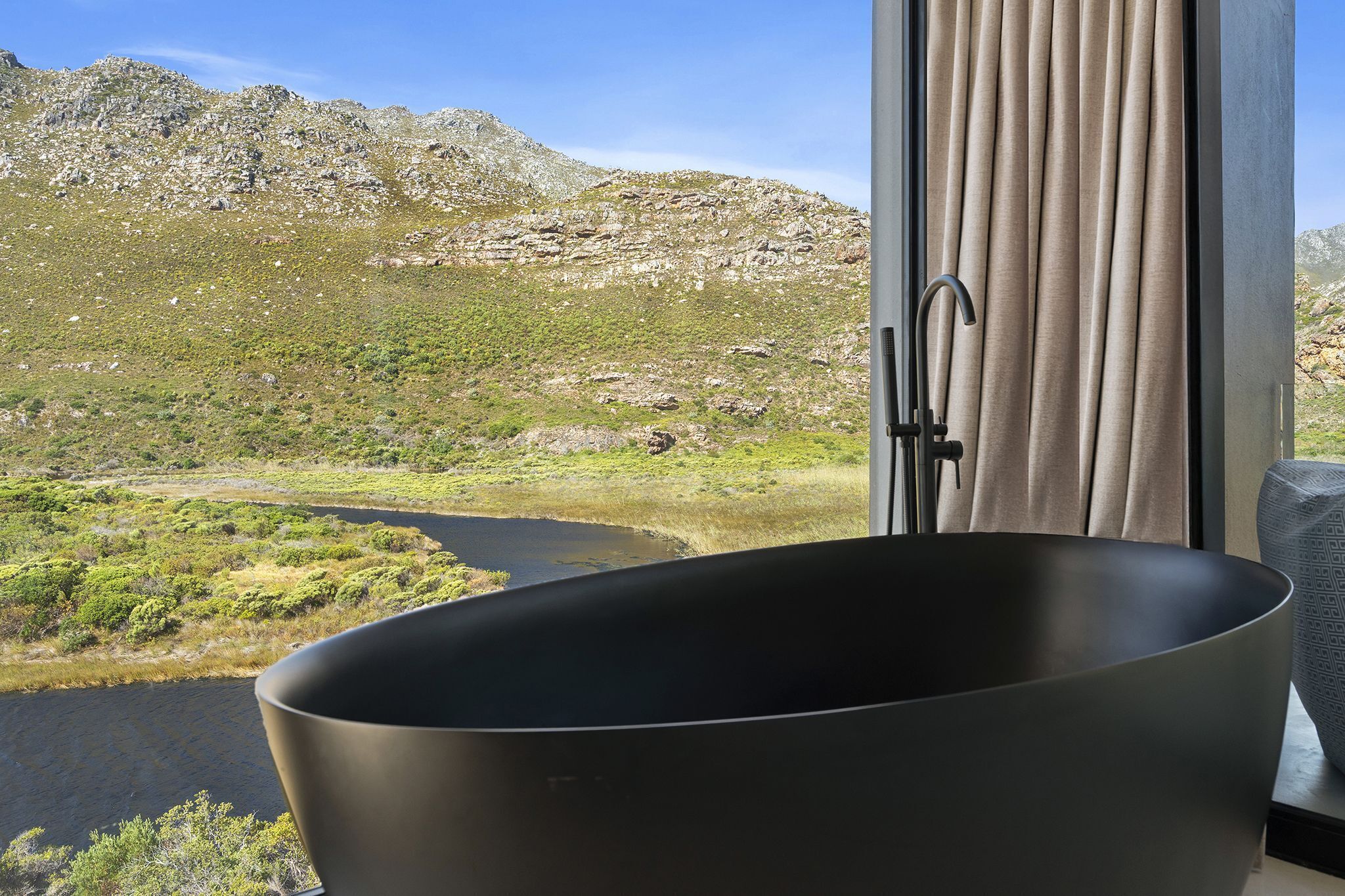 A bathtub with a view of a mountainous landscape and a river.