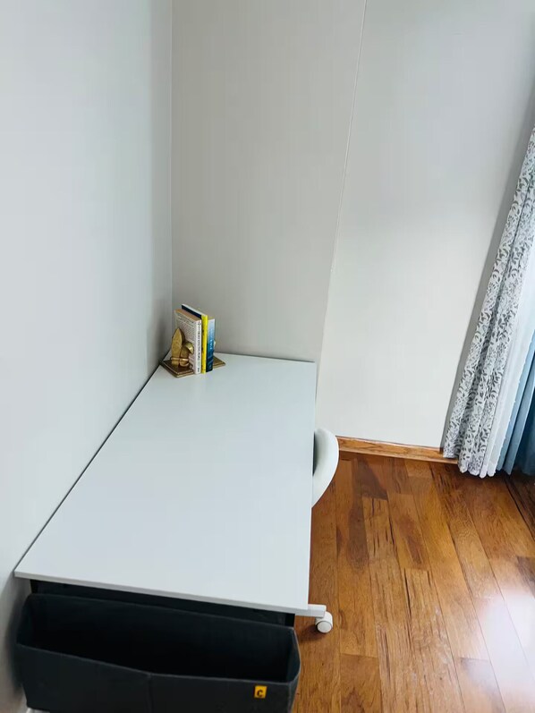 A small, white, corner desk with a black trash bin underneath. - 3-bedroom house in delightful Aurora with cool AC and comfort (Aurora)