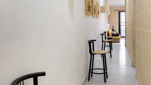 A hallway with chairs, a sofa, and a door leading to another room. - Traditional 2BR - Terrace Country Views (Qala)