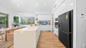 Eine moderne Küche mit weißen Schränken, einem schwarzen Kühlschrank und einem Holztisch.