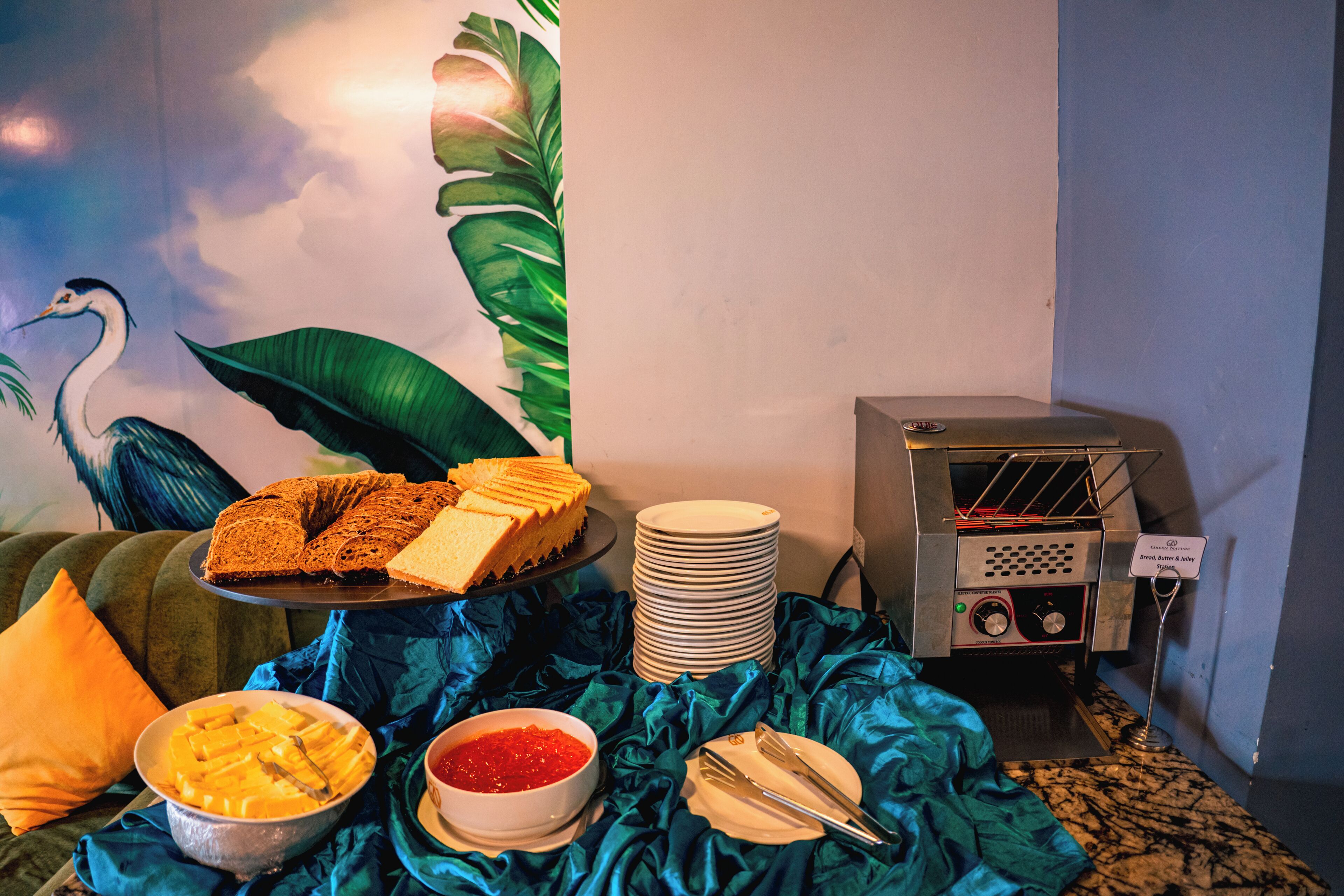 A buffet setup with a variety of food items, a stack of plates, and a toaster.