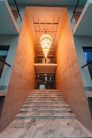 Una escalera de mármol con un candelabro, que conduce a la entrada de un edificio moderno.