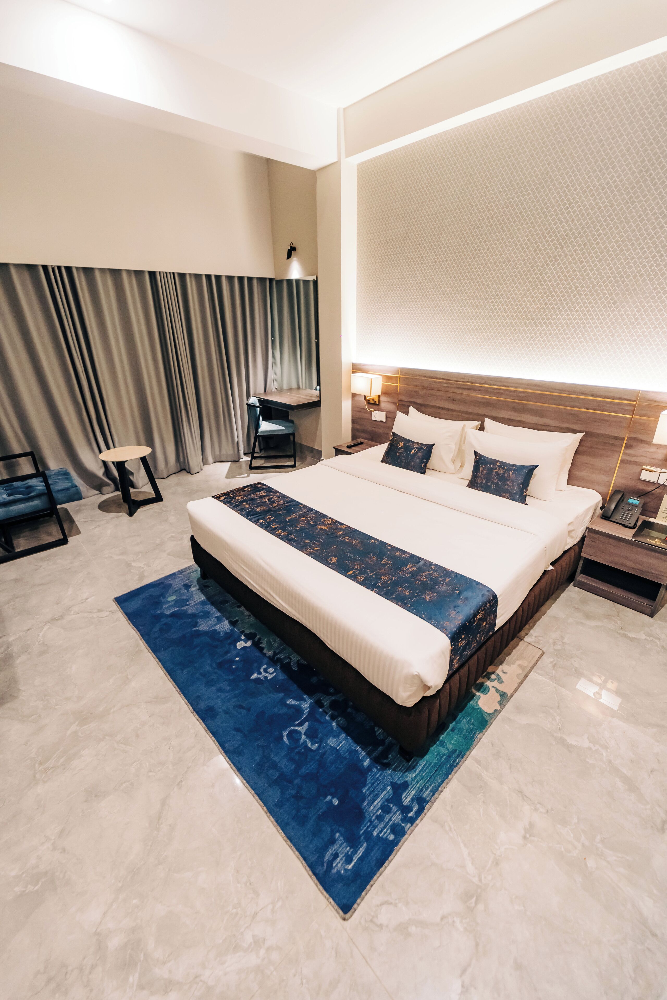A modern hotel room with a large bed, a desk, and a chair.