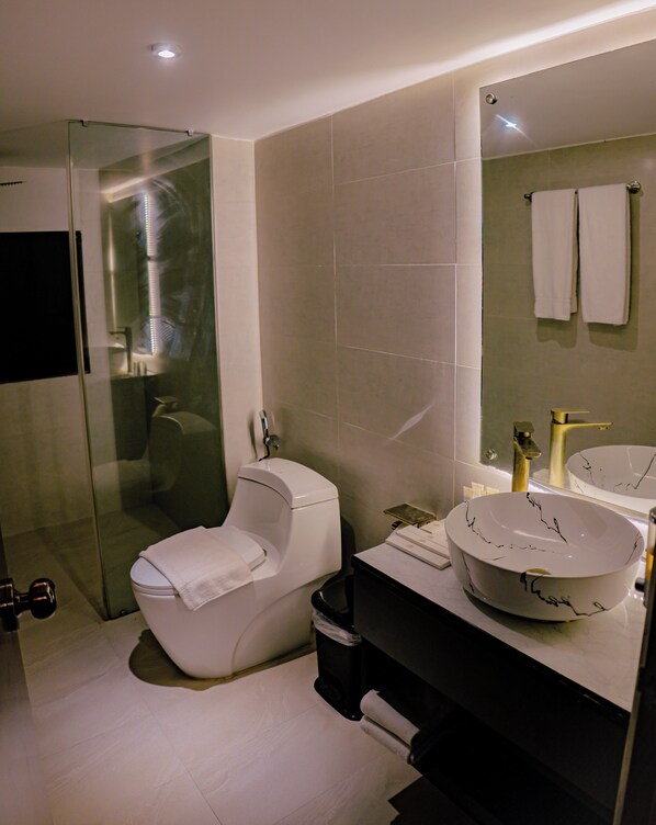 A modern bathroom with a glass-enclosed shower, a white toilet, a black sink with a white basin, and a mirror with two towels. - Green Nature Resort & Suites (Cox's Bazar)