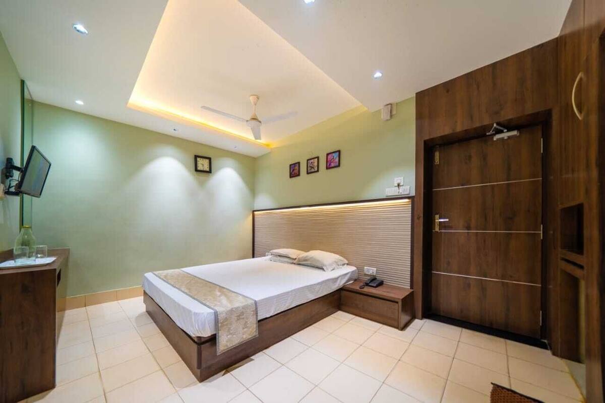 A bedroom with a bed, bedside table, nightstand, TV, and wardrobe.