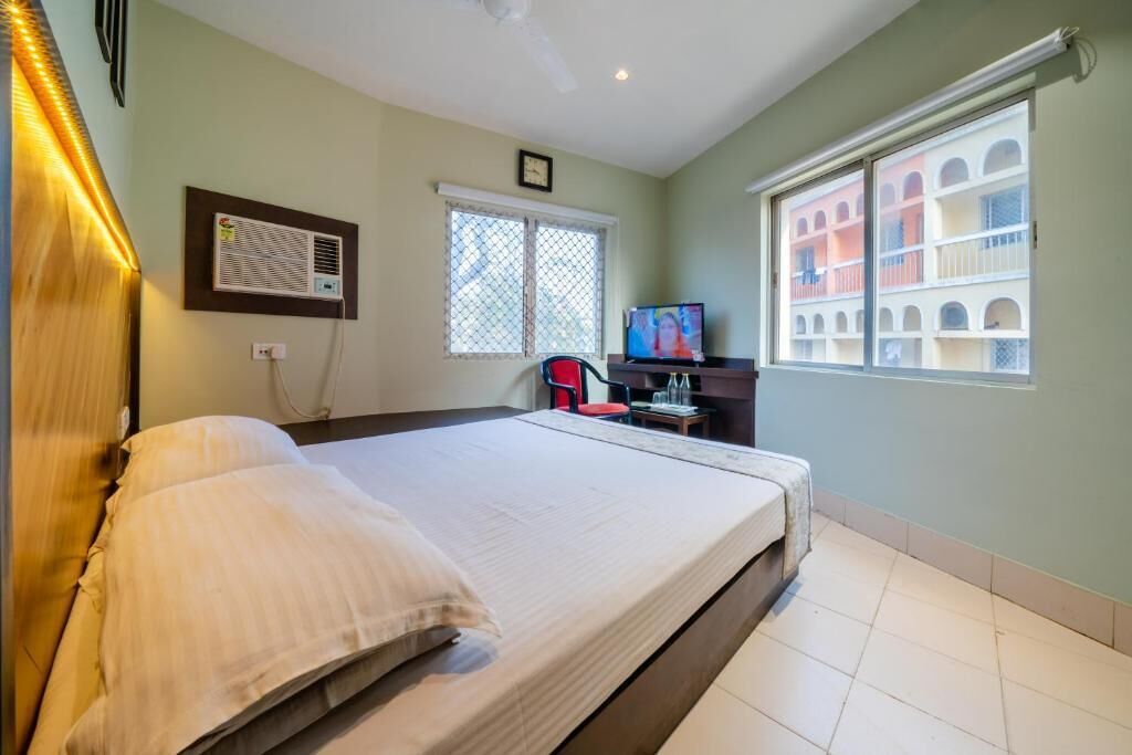 Hotelkamer met een bed, een televisie, een bureau en een raam met uitzicht op gebouwen.