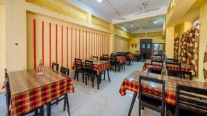 A restaurant with multiple tables and chairs, arranged in rows. - Hotel Dolphin Puri (Puri)