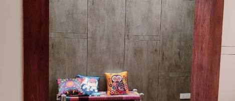 A room with a wooden bench, a wall-mounted camera, and a power outlet.