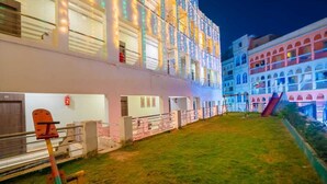 A multi-story hotel with balconies, a grassy courtyard, and a playground. - Hotel Dolphin Puri (Puri)