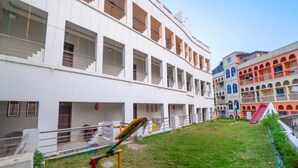 A multi-story building with balconies, a playground with exercise equipment, and a slide. - Hotel Dolphin Puri (Puri)