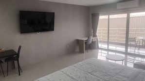 Una camera d'albergo con un letto, una scrivania con una sedia, un televisore a parete e un balcone con posti a sedere esterni.