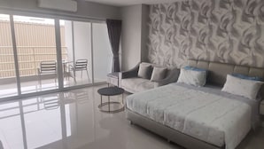 Una camera da letto moderna con un letto grande, un divano, un tavolino e vista all'esterno tramite una porta scorrevole.