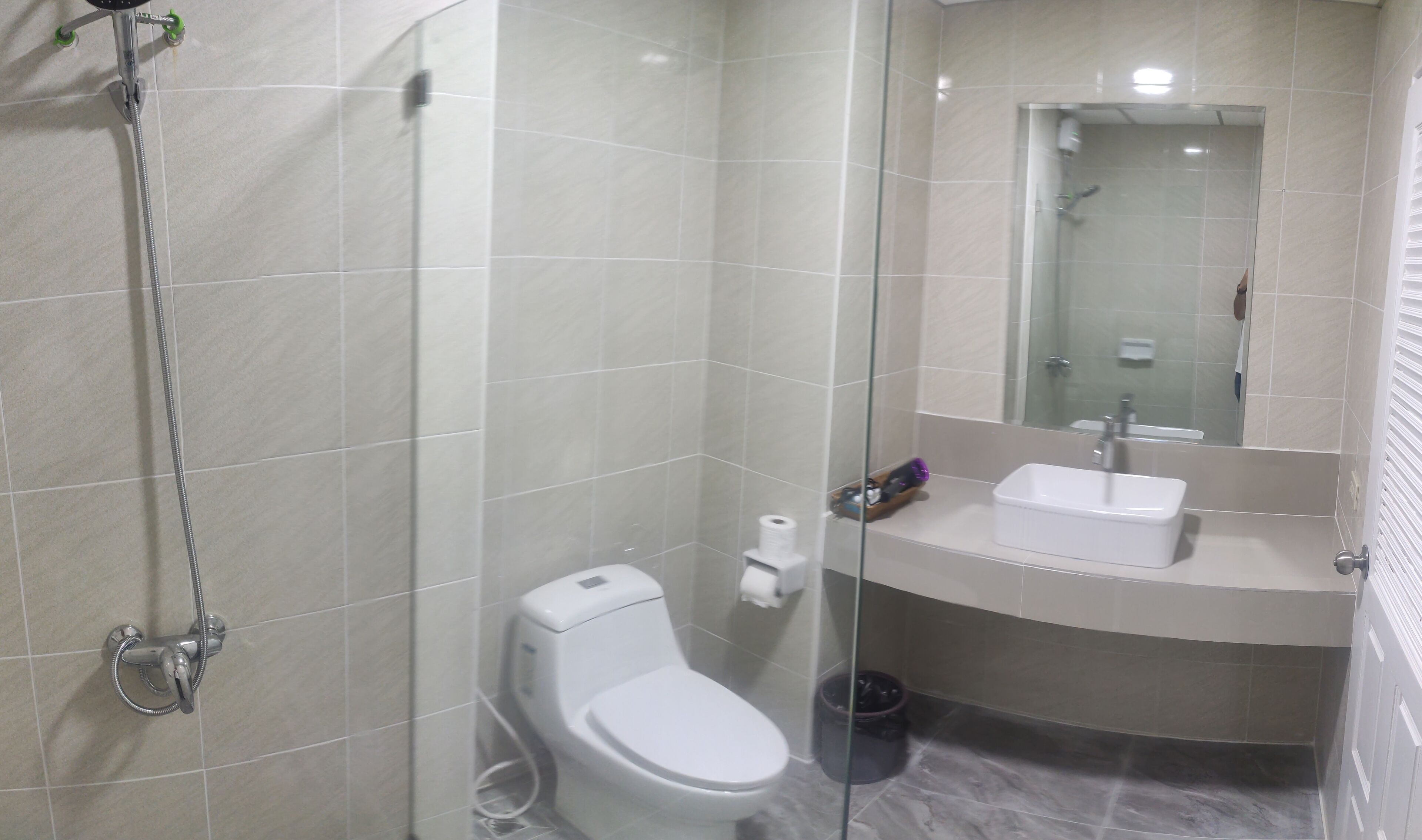 A modern bathroom with a glass-enclosed shower, a toilet, and a sink.