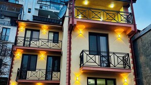Un immeuble à plusieurs étages doté de balcons, d’un éclairage extérieur et d’une antenne parabolique.