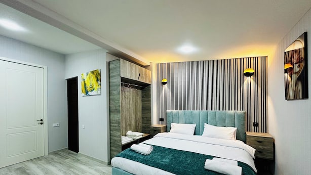 Une chambre à coucher moderne avec un grand lit, une armoire et un miroir.