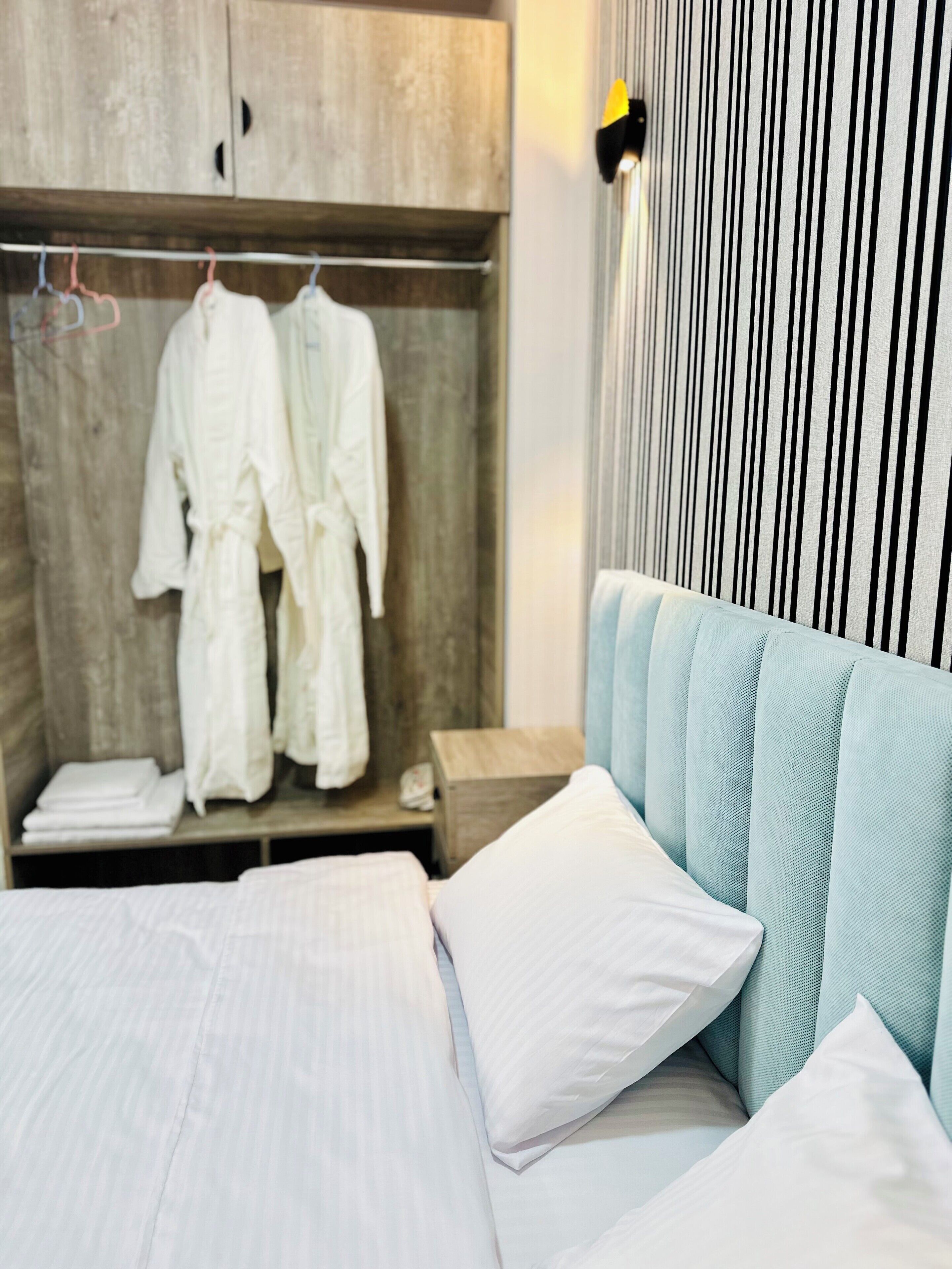 A hotel room with a bed, a wooden wardrobe, and a striped wall.