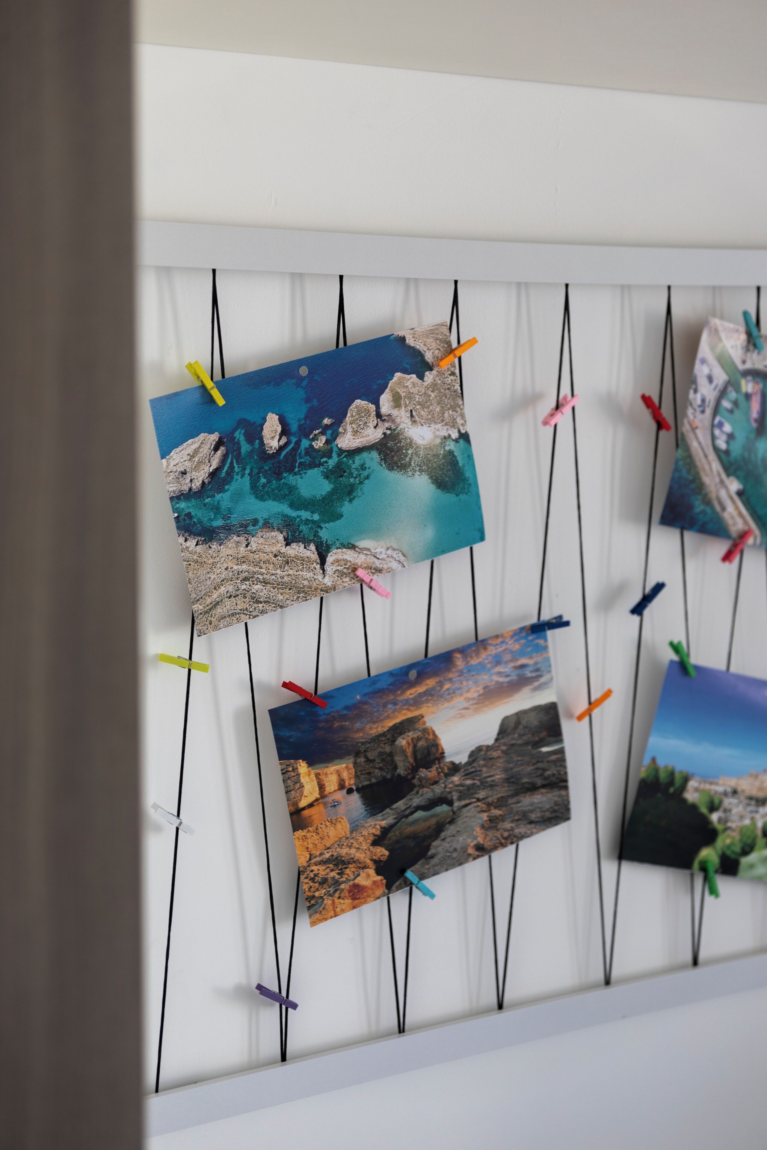 A wall with photographs pinned up using clothespins.