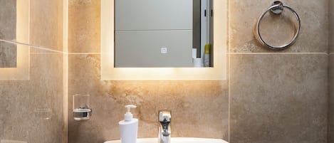 A bathroom with a pedestal sink, a mirror, and a towel ring.