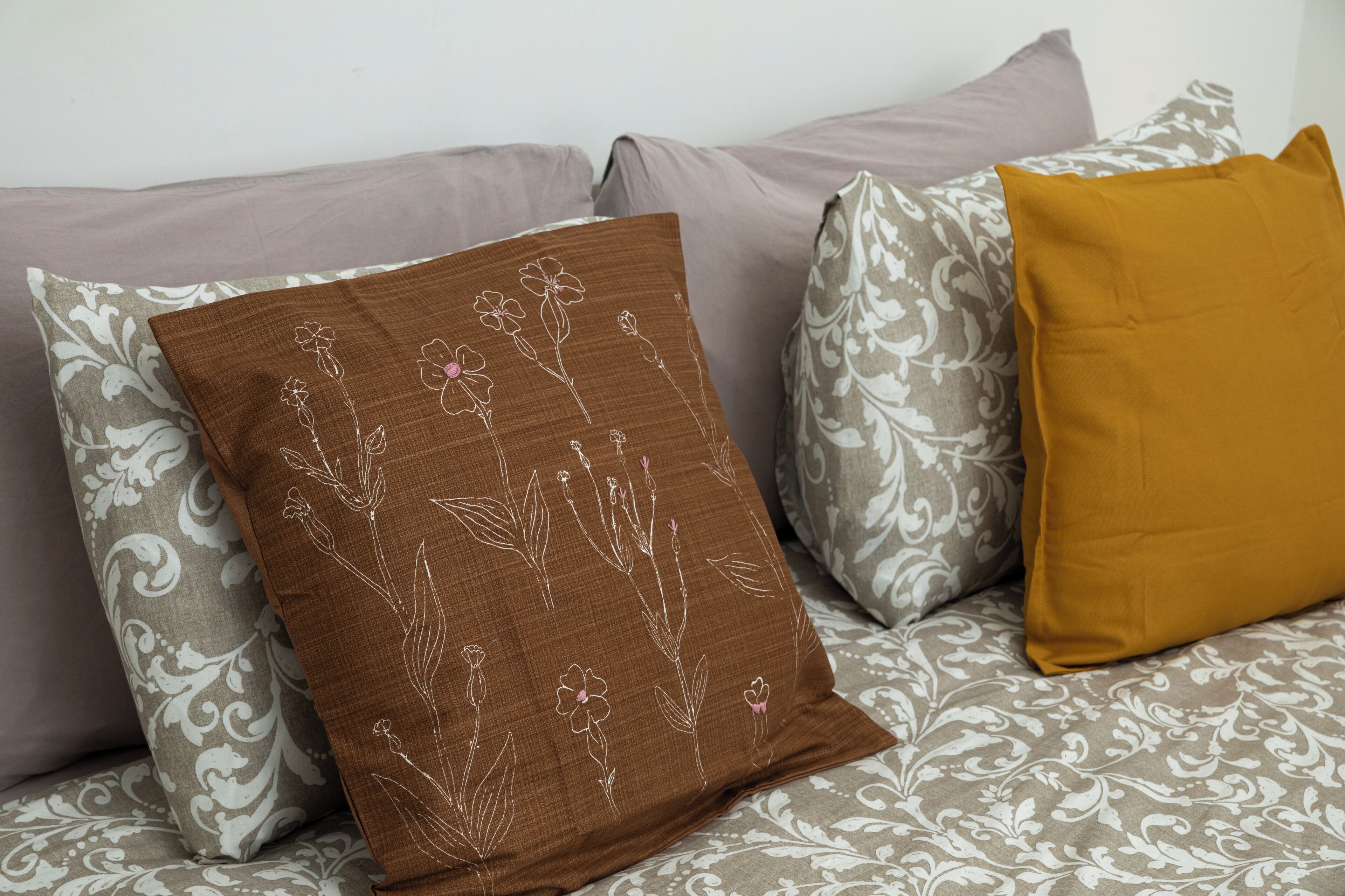 Een bed met beddengoed met patroon en decoratieve kussens.