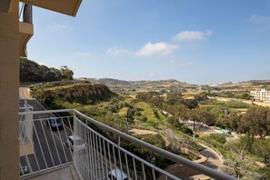 A balcony with a view of a hilly landscape, a road, and a building in the distance. - 3BR Country Retreat with Large Terrace (Zebbug)