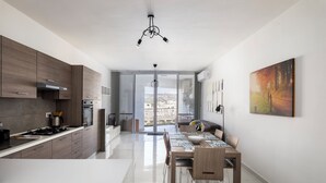 A modern kitchen with a dining area, large windows, and a city view. - 3BR Country Retreat with Large Terrace (Zebbug)