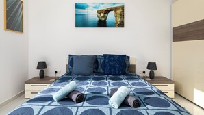 A modern bedroom with a large bed, two bedside tables, and a wall-mounted artwork of a natural rock formation. - 3BR Country Retreat with Large Terrace (Zebbug)