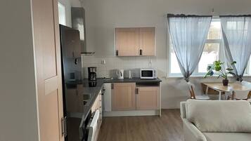 A compact kitchen with a microwave, coffee maker, and a dining area with a table and chairs.