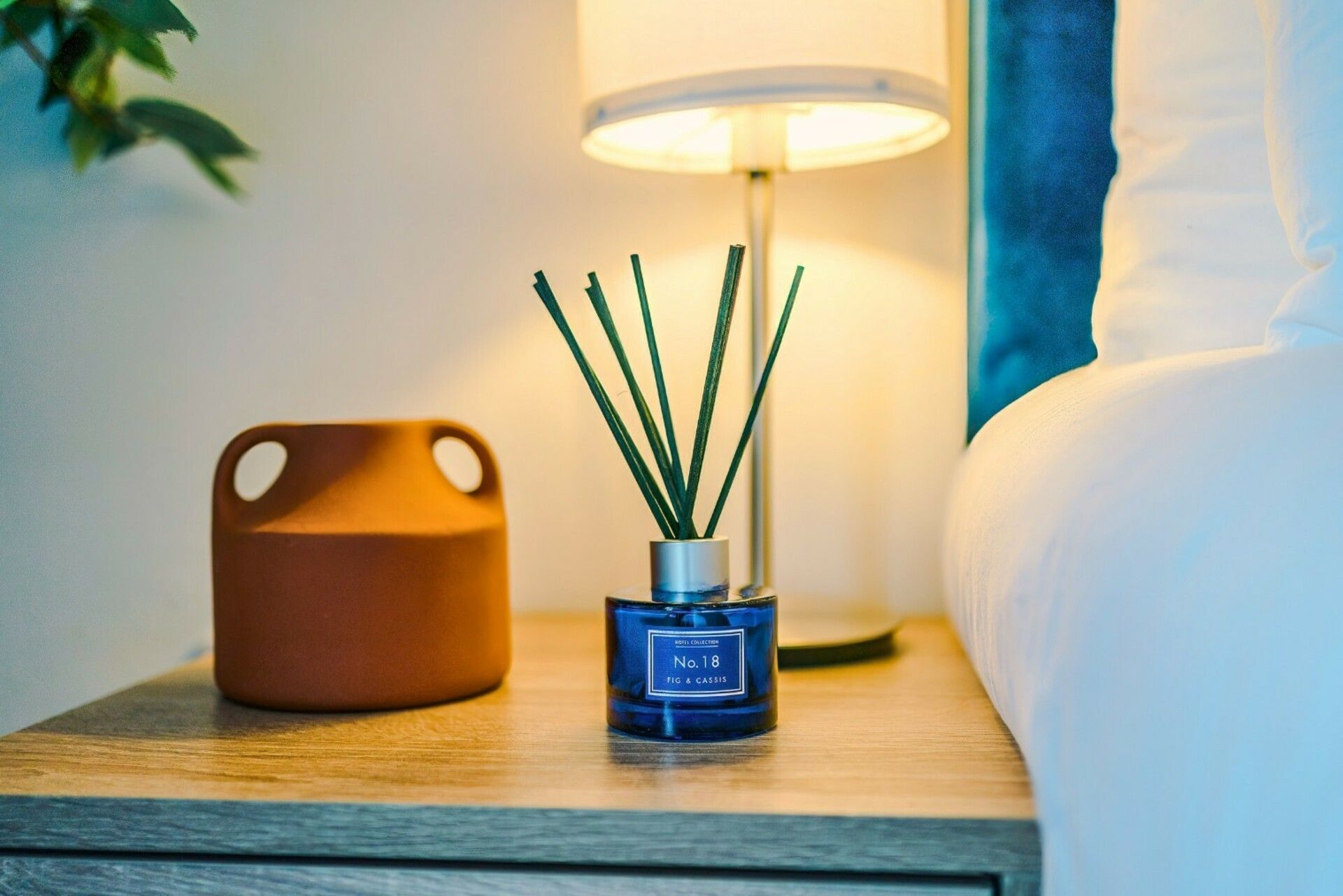 A bedside table with a blue candle holder labeled 'No. 18' and a brown decorative object.