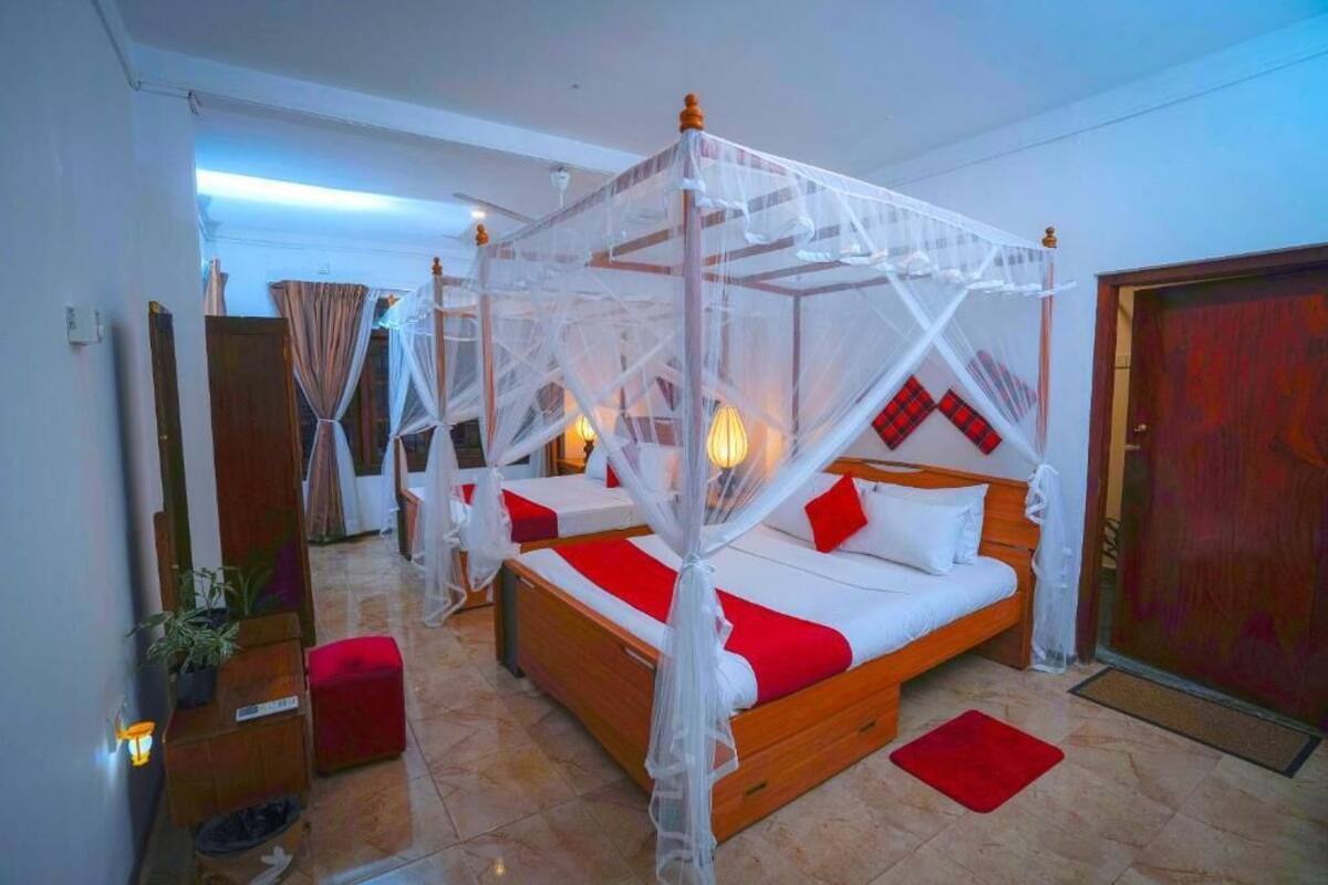 Une chambre d’hôtel avec un lit à baldaquin, une décoration aux couleurs rouge et blanche et un plancher en bois.
