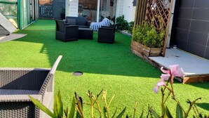 Um jardim no terraço com grama sintética, móveis de exterior e uma estrutura de estufa.