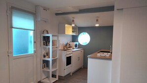 Uma cozinha compacta com armários brancos, micro-ondas e cafeteira na bancada.