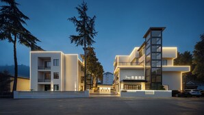 A modern hotel with a multi-story structure, balconies, and a well-lit entrance. - Zhangjiajie JIMO HOTEL (Zhangjiajie)
