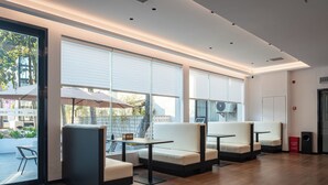 A modern indoor seating area with cushioned chairs and tables, large windows, and a clean, minimalist design. - Zhangjiajie JIMO HOTEL (Zhangjiajie)