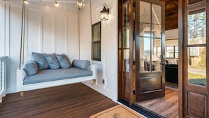 Interior de madera con un asiento mecedora, una puerta con paneles de vidrio y un felpudo.