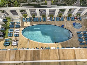 Vista aérea de una zona de piscina de hotel con múltiples tumbonas y una piscina central.
