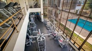 A gym with treadmills, weight machines, and a pool visible through large windows. - Villa Ocean Dream 3BR Oasis and guesthouse (Sosúa)