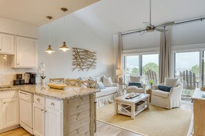 Eine geräumige Küche mit weißen Schränken, einer Granit Arbeitsplatte und einem Essbereich mit Tisch und Stühlen.