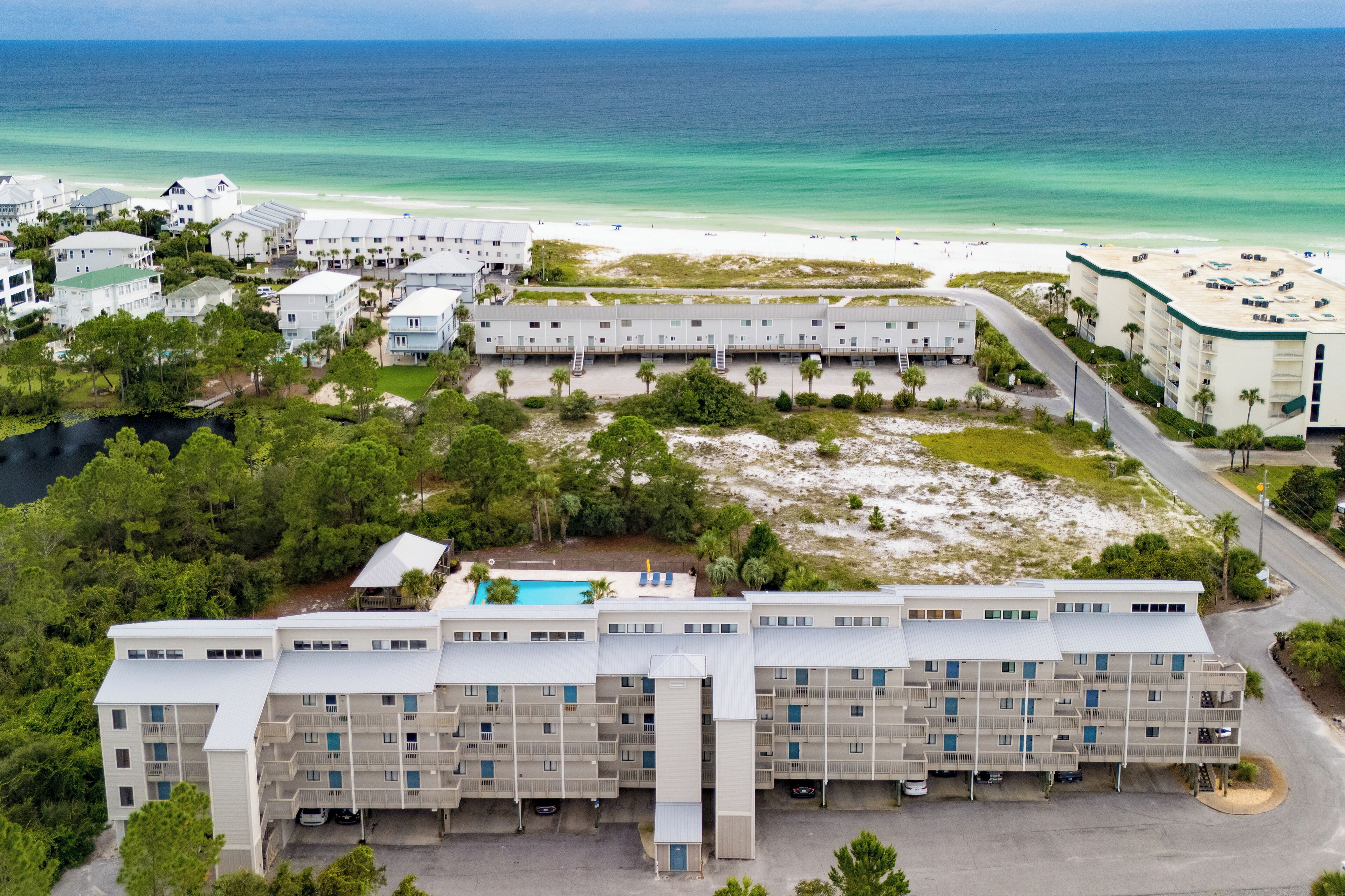 Un hôtel à plusieurs étages doté d’une piscine, situé près d’une plage aux eaux bleues et cristallines.