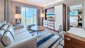 A modern hotel room with a sofa, a round table, a TV, and a bed. - Cozy Oasis in a Luxury Hotel w/Daily Cleaning (Fort Lauderdale)