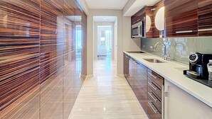 A modern kitchen with wooden cabinetry, stainless steel appliances, and a large window. - Cozy Oasis in a Luxury Hotel w/Daily Cleaning (Fort Lauderdale)