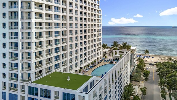 A high-rise hotel with a rooftop pool, ocean view, and a beach area with umbrellas. - Cozy Oasis in a Luxury Hotel w/Daily Cleaning (Fort Lauderdale)