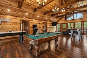 A wooden interior with a pool table, foosball table, and bar area. - Group Retreat | Sleeps 28 | Indoor Pool + Spa + Game Room | Green Mountain Lodge (Pigeon Forge)