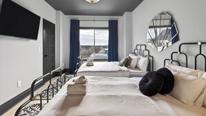 A hotel room with two beds, a large window with curtains, a flat-screen TV, a mirror, and a ceiling light fixture. - Hottub + Speakeasy Lounge + Premium Karaoke + Rooftop + Near Downtown Nashville (Nashville)