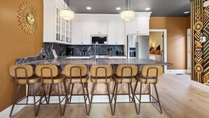 A modern kitchen with a large island, bar stools, and pendant lighting. - Hottub + Speakeasy Lounge + Premium Karaoke + Rooftop + Near Downtown Nashville (Nashville)
