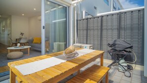 A modern patio with a wooden table, a bench, and a stroller. - Relax by the Beach, Close to Everything - Minutes from City & Airport! (Flinders Park)