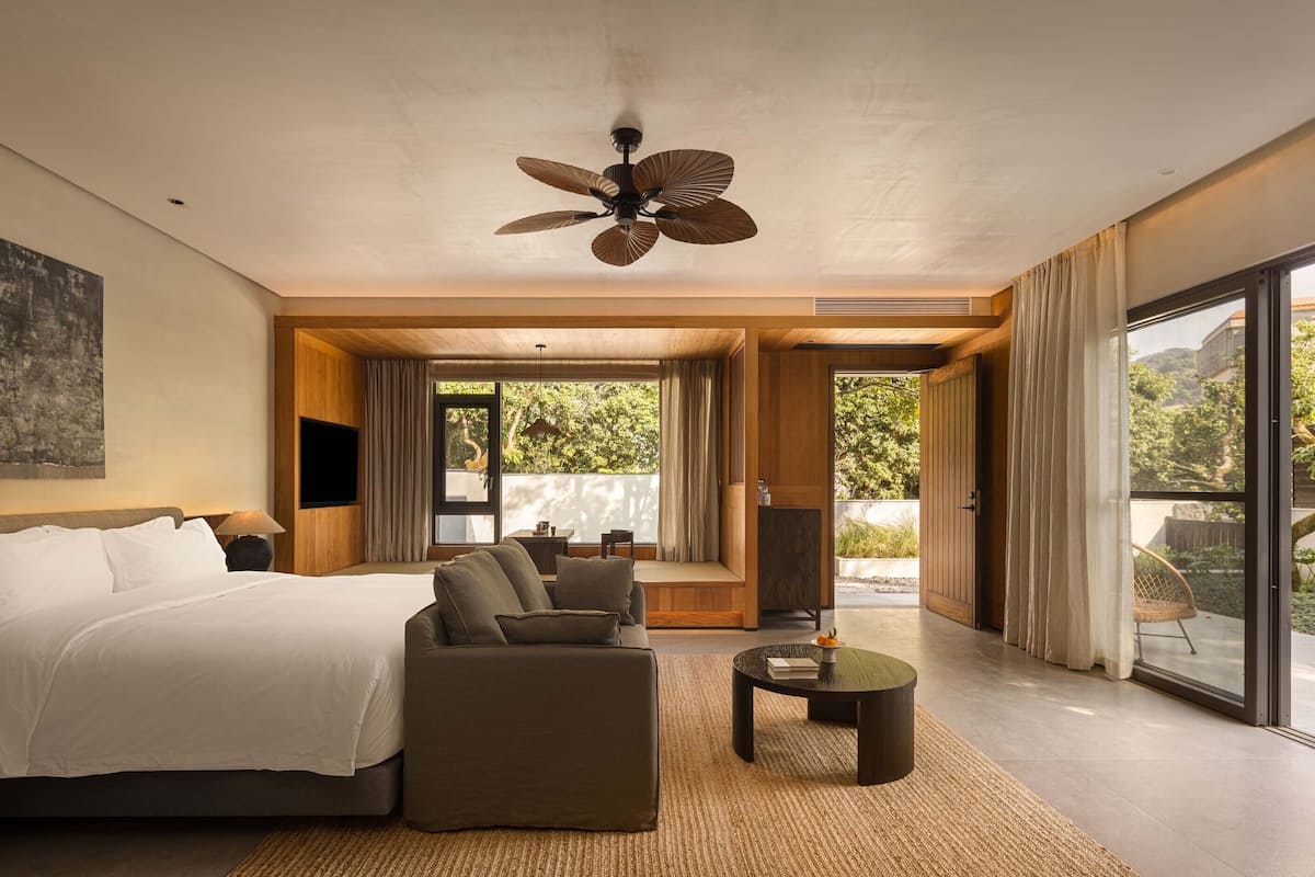 Un dormitorio moderno con cama, sofá y ventilador de techo.
