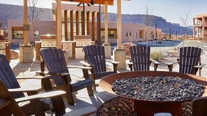 Un espace extérieur aménagé avec des chaises Adirondack et un foyer, offrant une vue sur un paysage montagneux.