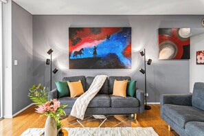 A modern living room with a grey sofa, a coffee table, and a painting of a horse and rider.