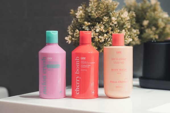 Three bottles of body wash on a white surface with a blurred background.