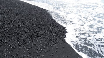 Una playa con piedras negras y olas.